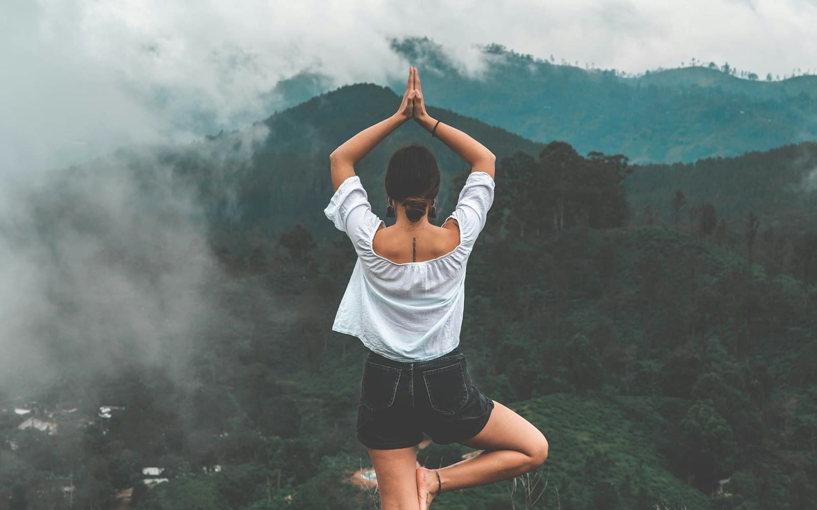 Tree pose on a misty mountaintop, hands at heart