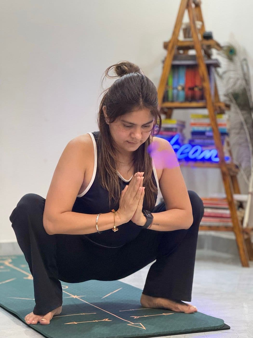 Shilpa in a deep squat with hands at heart centre