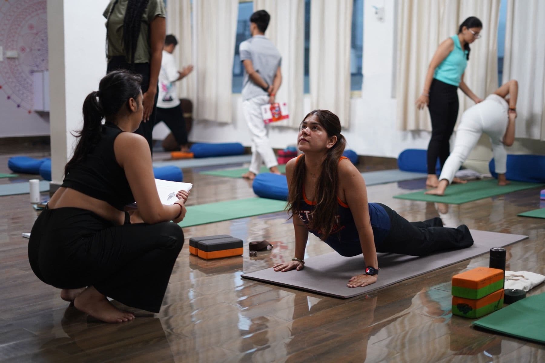 Shilpa guiding a student one-to-one through a backbend
